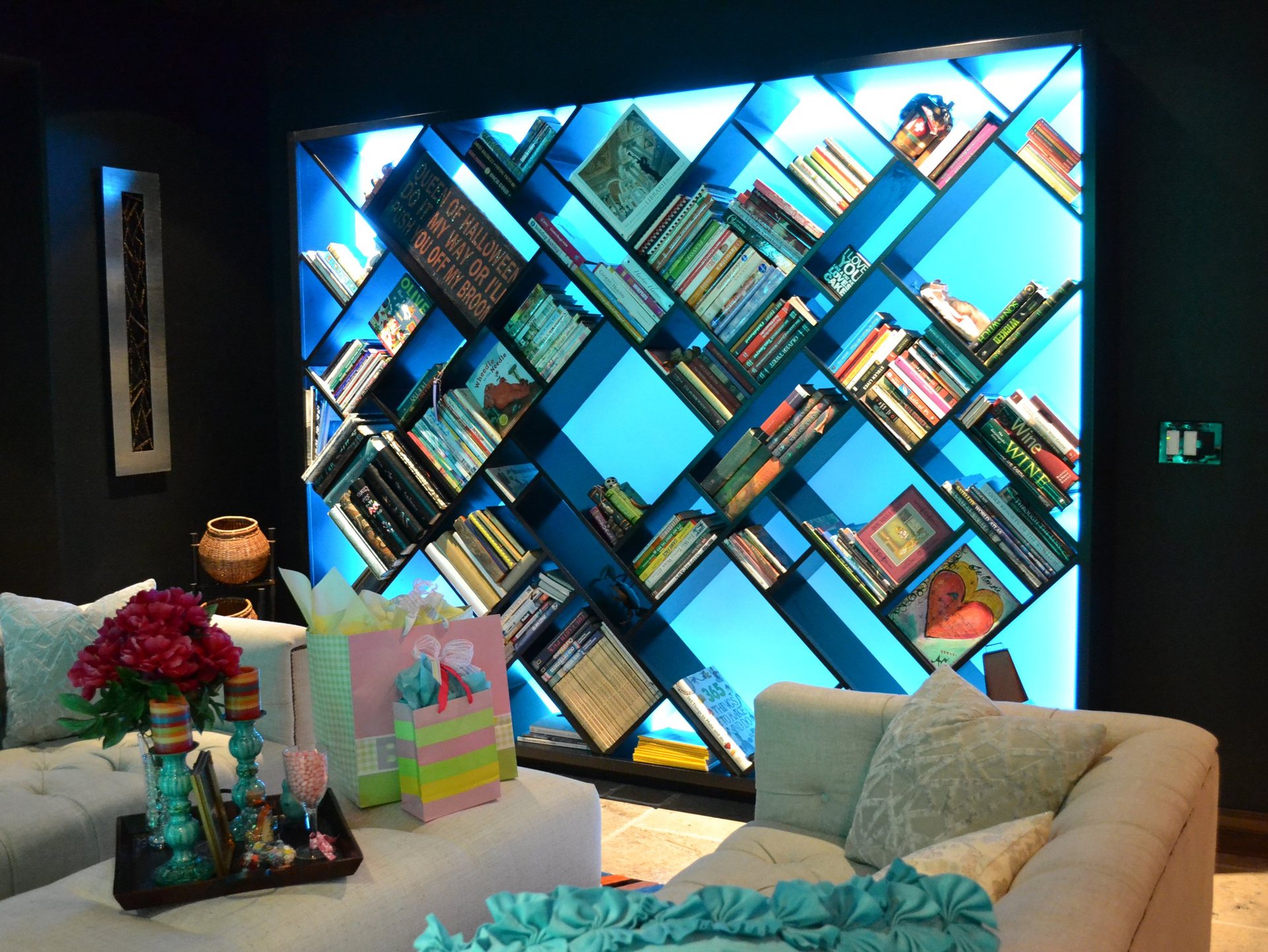 Backlit diagonal built-in bookshelf spanning a full wall in a residential media room