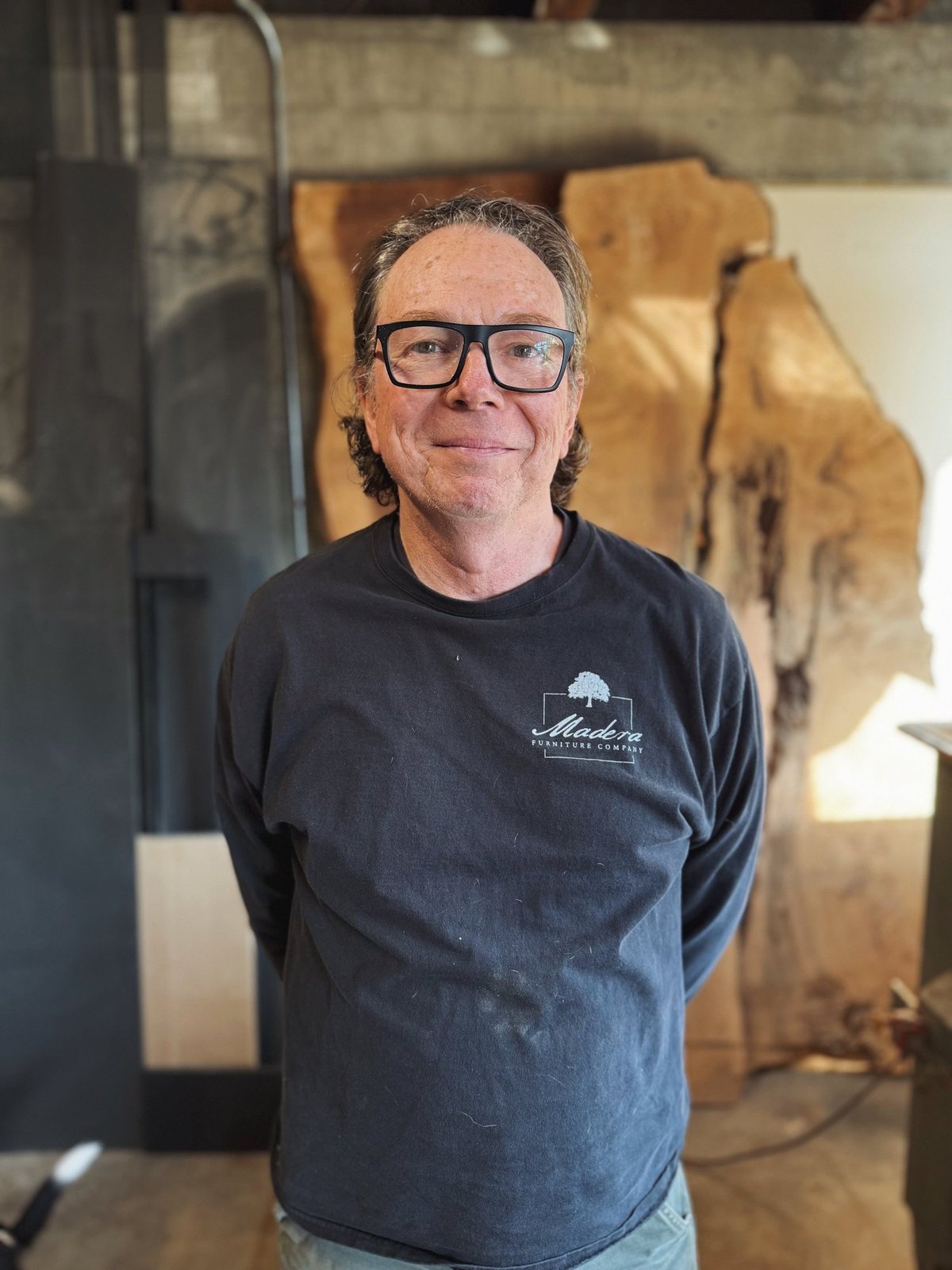 Carlos Taylor-Swanson, founder of Madera Furniture Company, in the Tacoma studio beside a live-edge slab