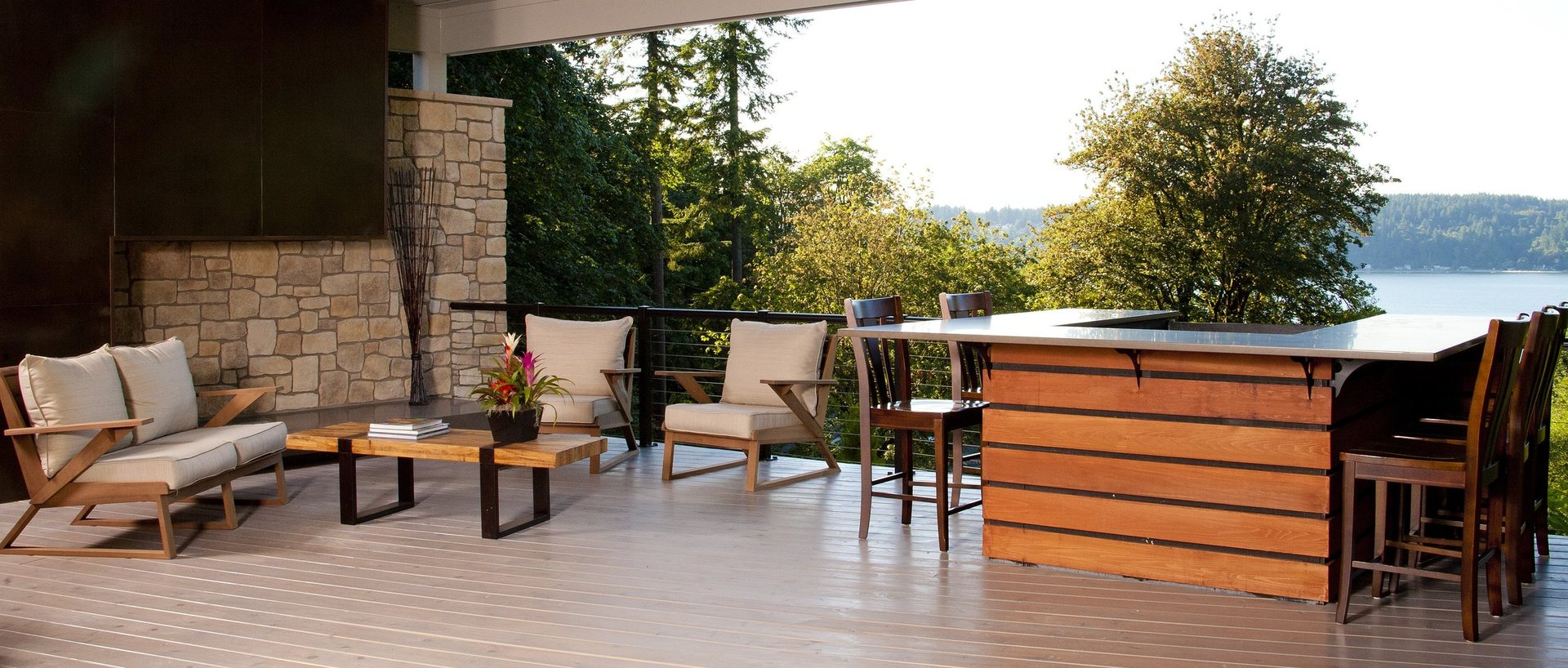 Covered outdoor terrace with teak lounge seating and a cedar-clad bar overlooking Puget Sound