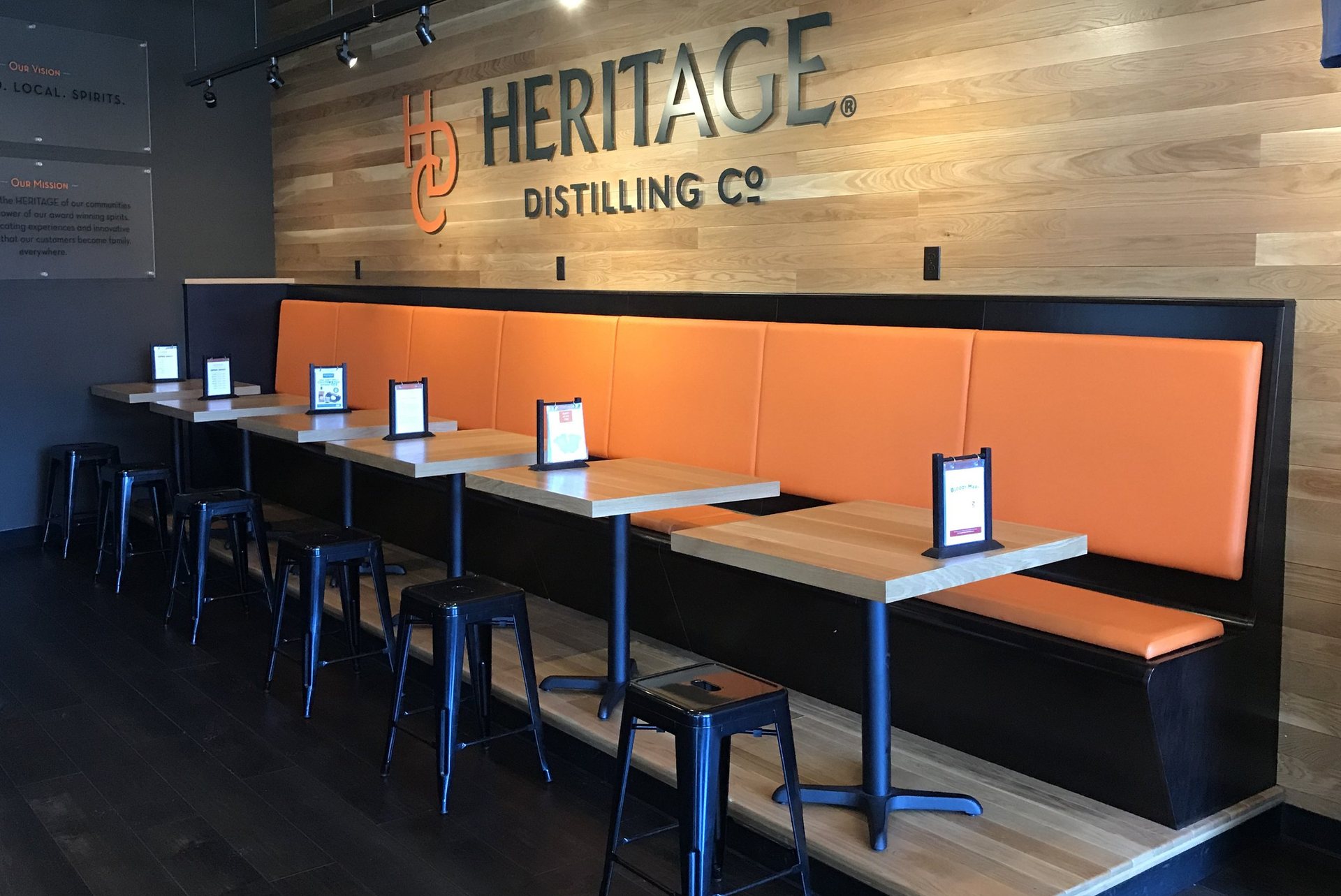 Distillery tasting room banquette with ash table tops and a reclaimed wood feature wall