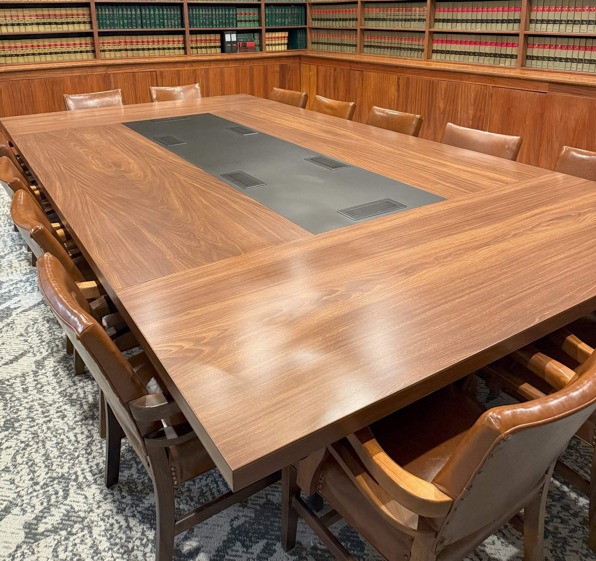 Custom walnut boardroom table with an inset leather writing surface and integrated power in a law library